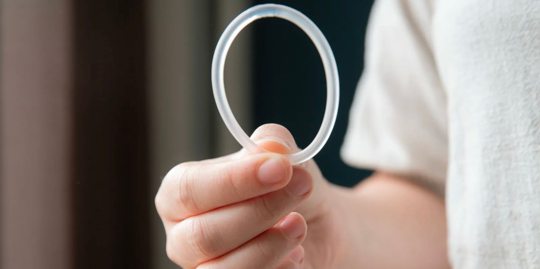 Mano sostiene un anillo vaginal anticonceptivo transparente