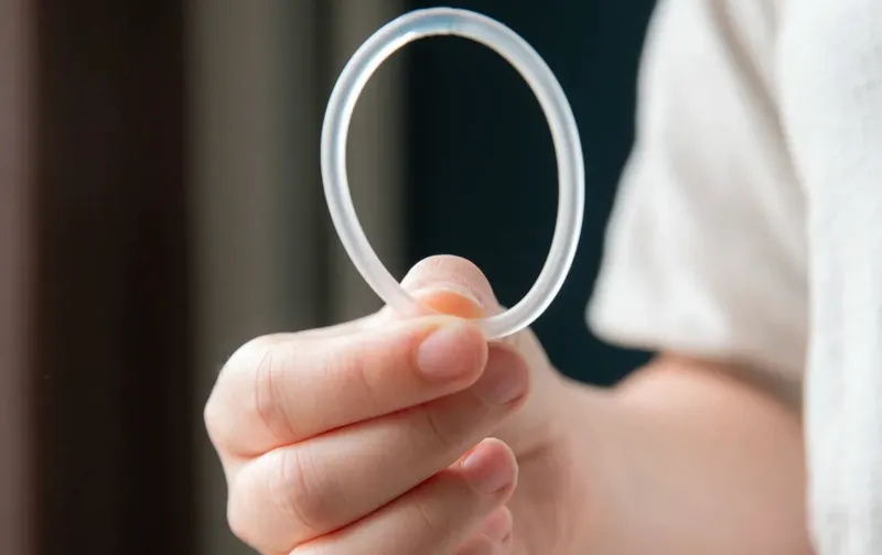Mano sostiene un anillo vaginal anticonceptivo transparente