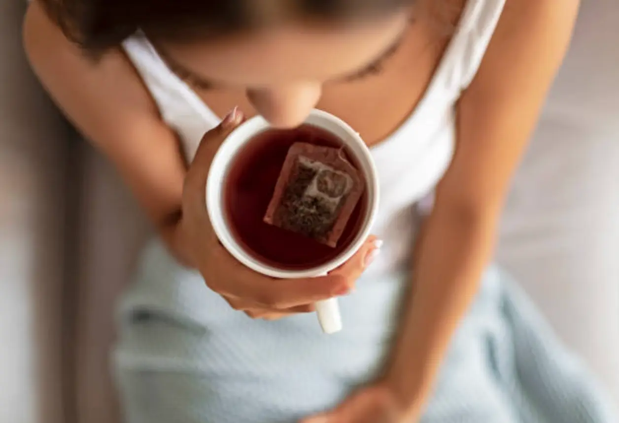 Mujer sostiene una taza de infusión con la bolsita dentro