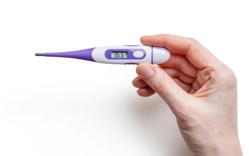 Mano sostiene un termómetro digital que marca 36,6 grados