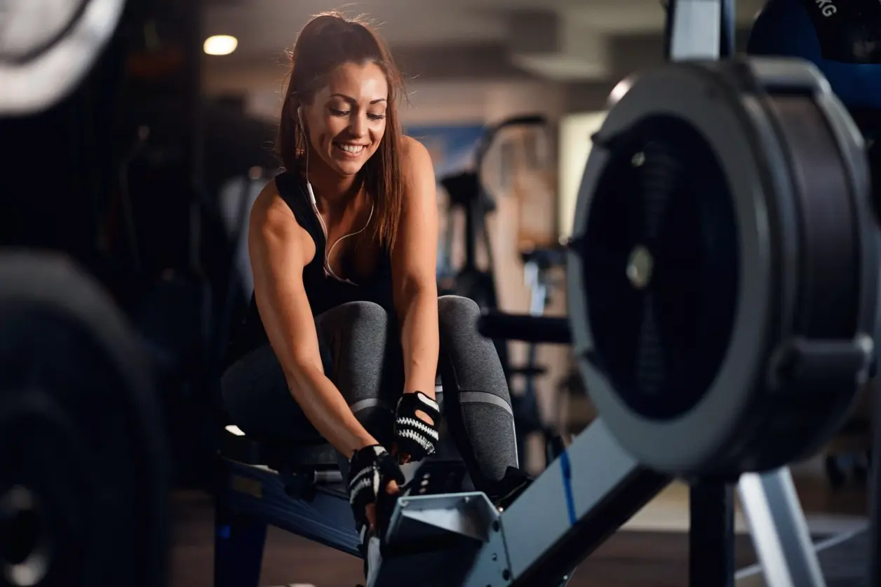 Mujer sonriente entrena en una máquina de remo en el gimnasio