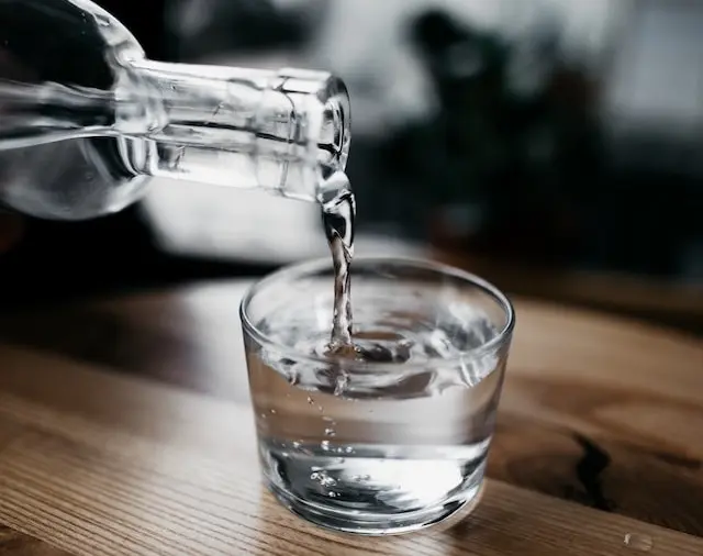 Agua vertida de una botella de cristal en un vaso