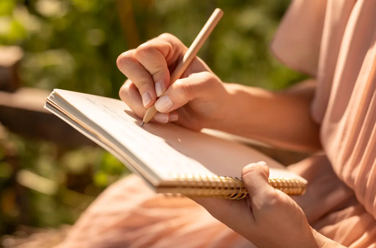Mujer escribe a lápiz en una libreta