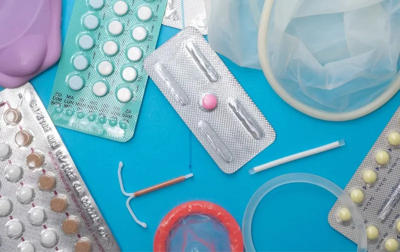 Blísteres de pastillas, preservativos, anillo vaginal y DIU sobre fondo azul