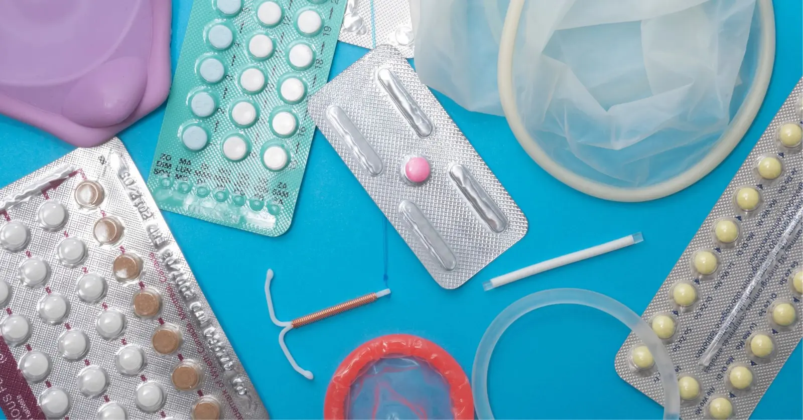 Blísteres de pastillas, preservativos, anillo vaginal y DIU sobre fondo azul