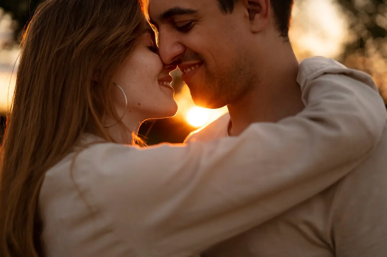 Pareja abrazada frente a frente al atardecer