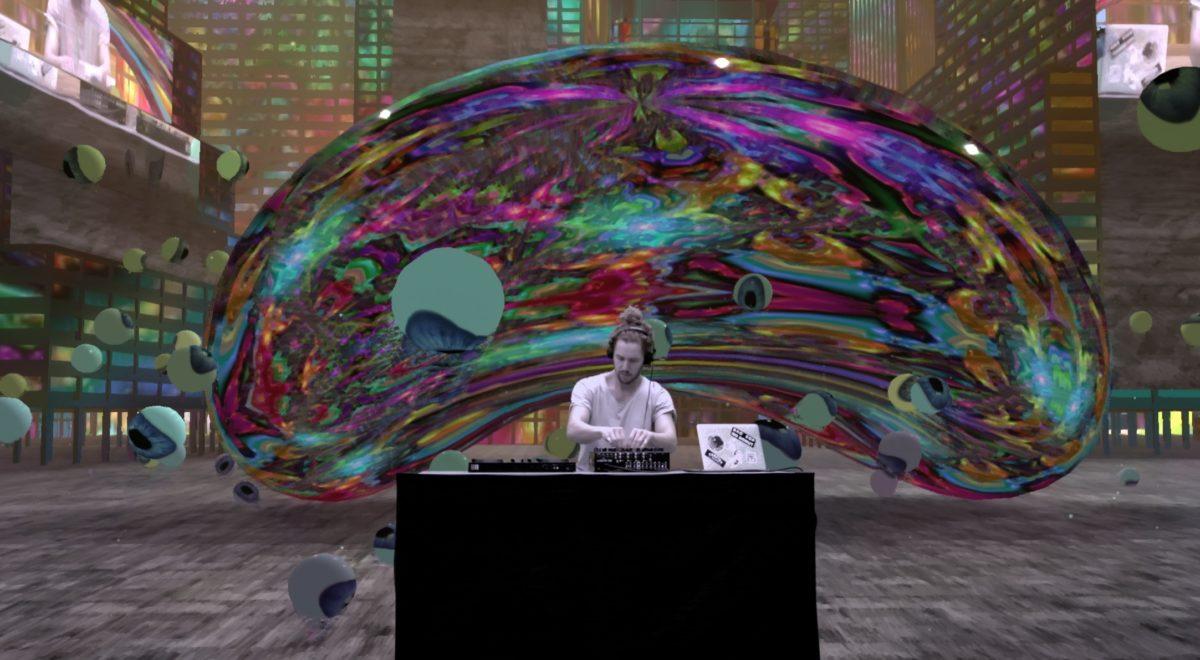 A DJ plays music amongst a digital environment with a large, iridescent chrome bean in an urban landscape.