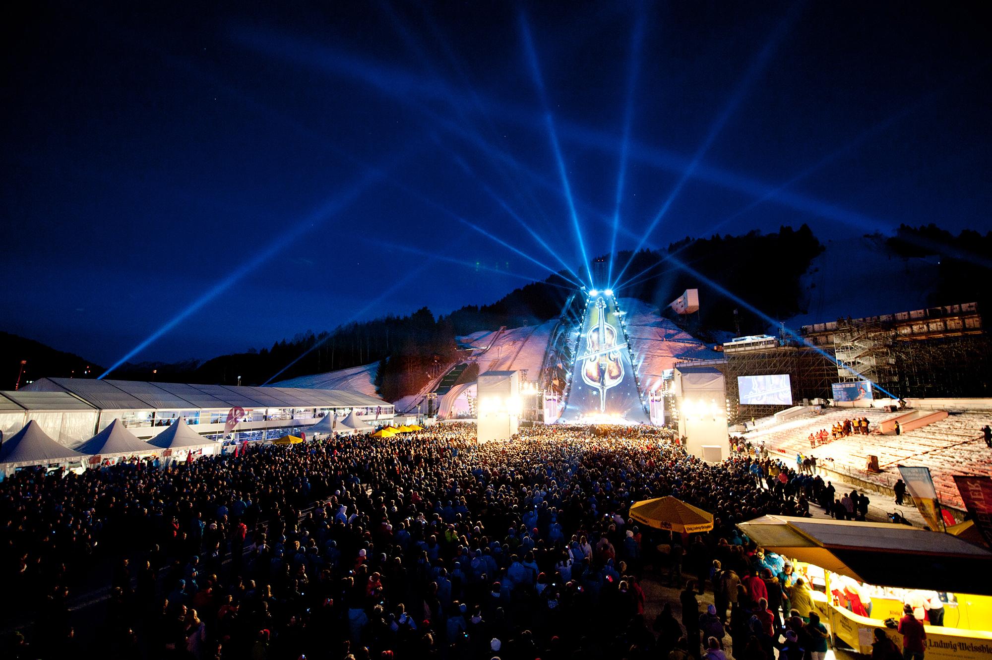 A violin is projection mapped onto the ski slope as a sea of people looks on.
