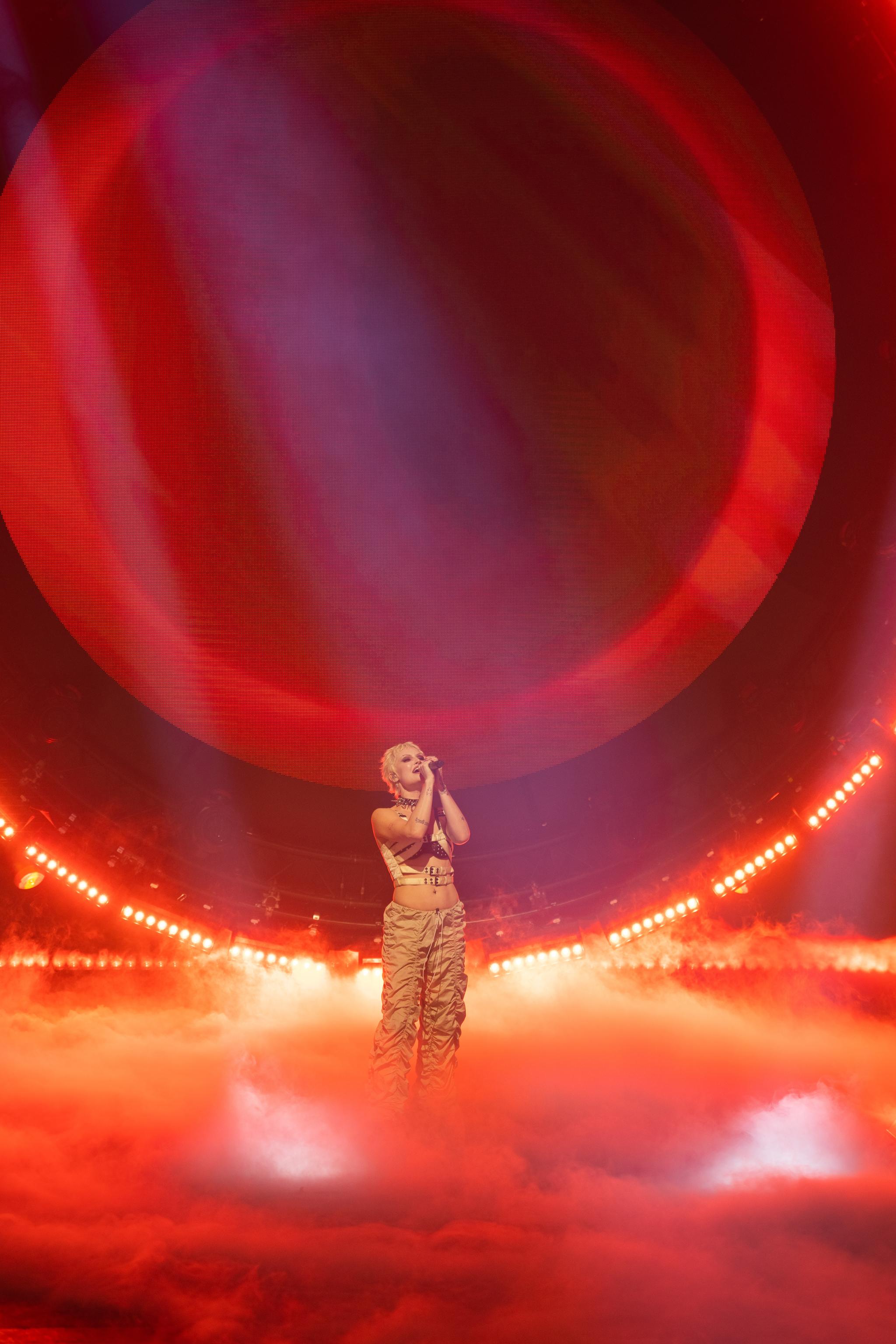 The singer Cassyette performs in front of a large light installation.