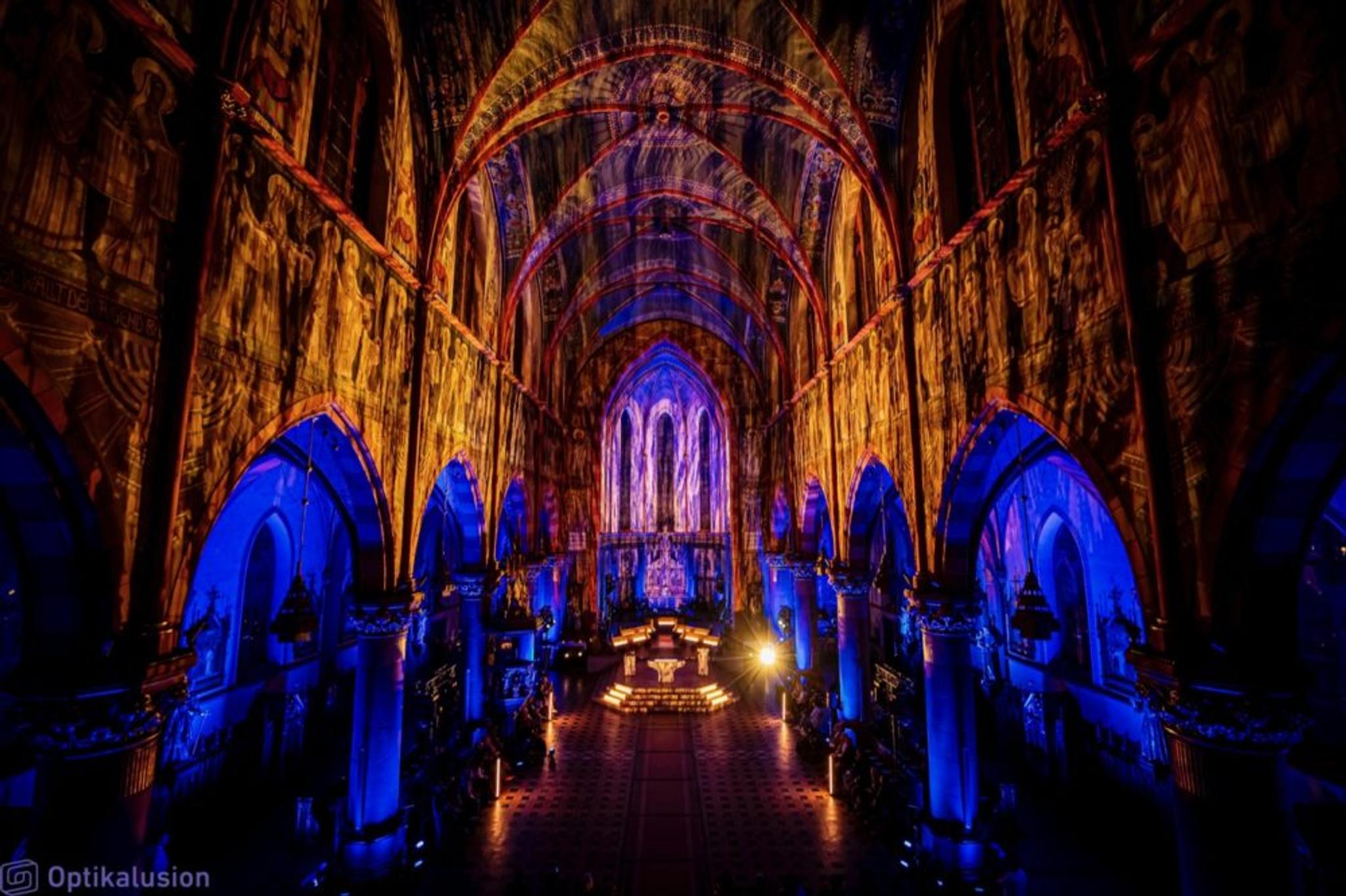 A large cathedral lit in blue and yellow.