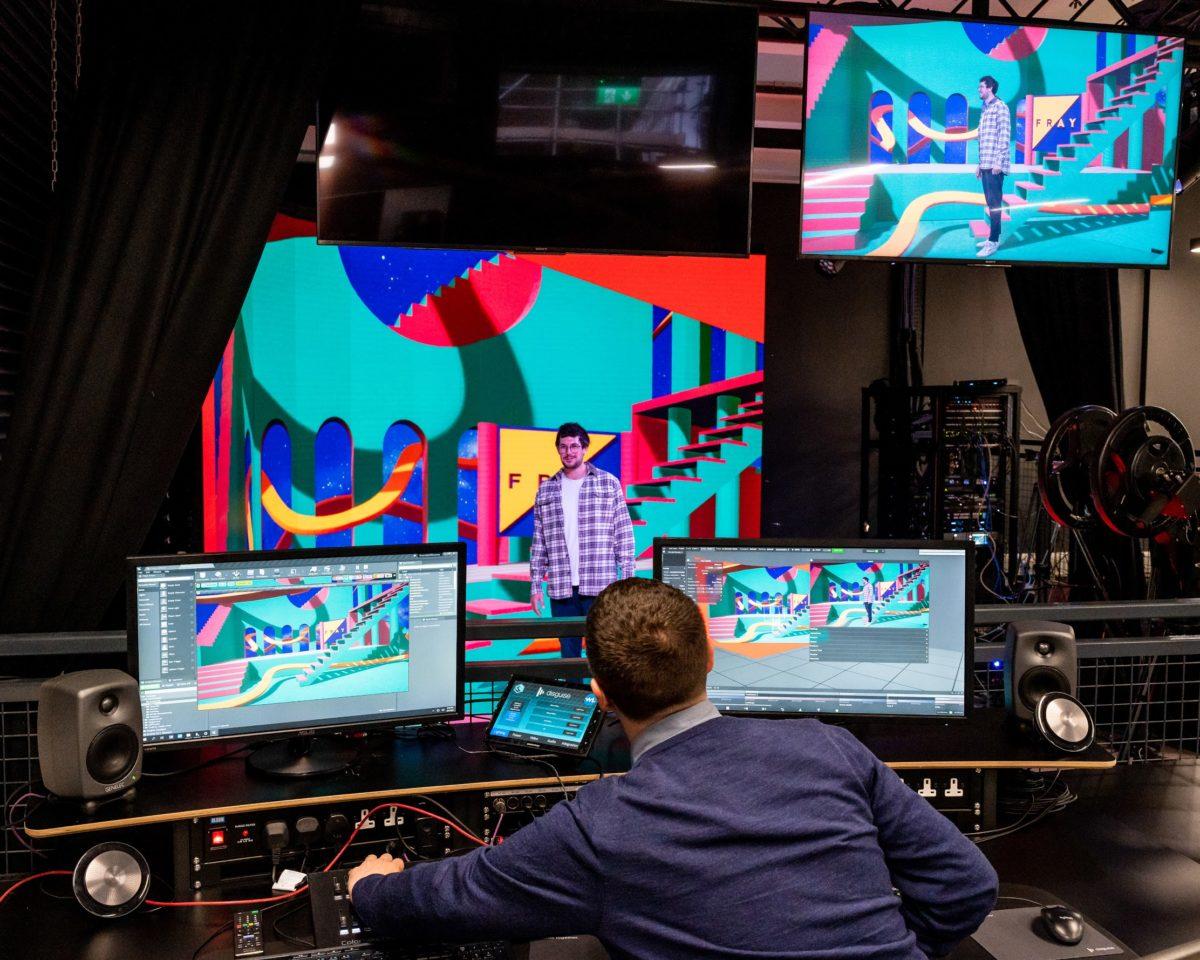 A technical director views a person on many monitors that is immersed in a colorful, digital stage.