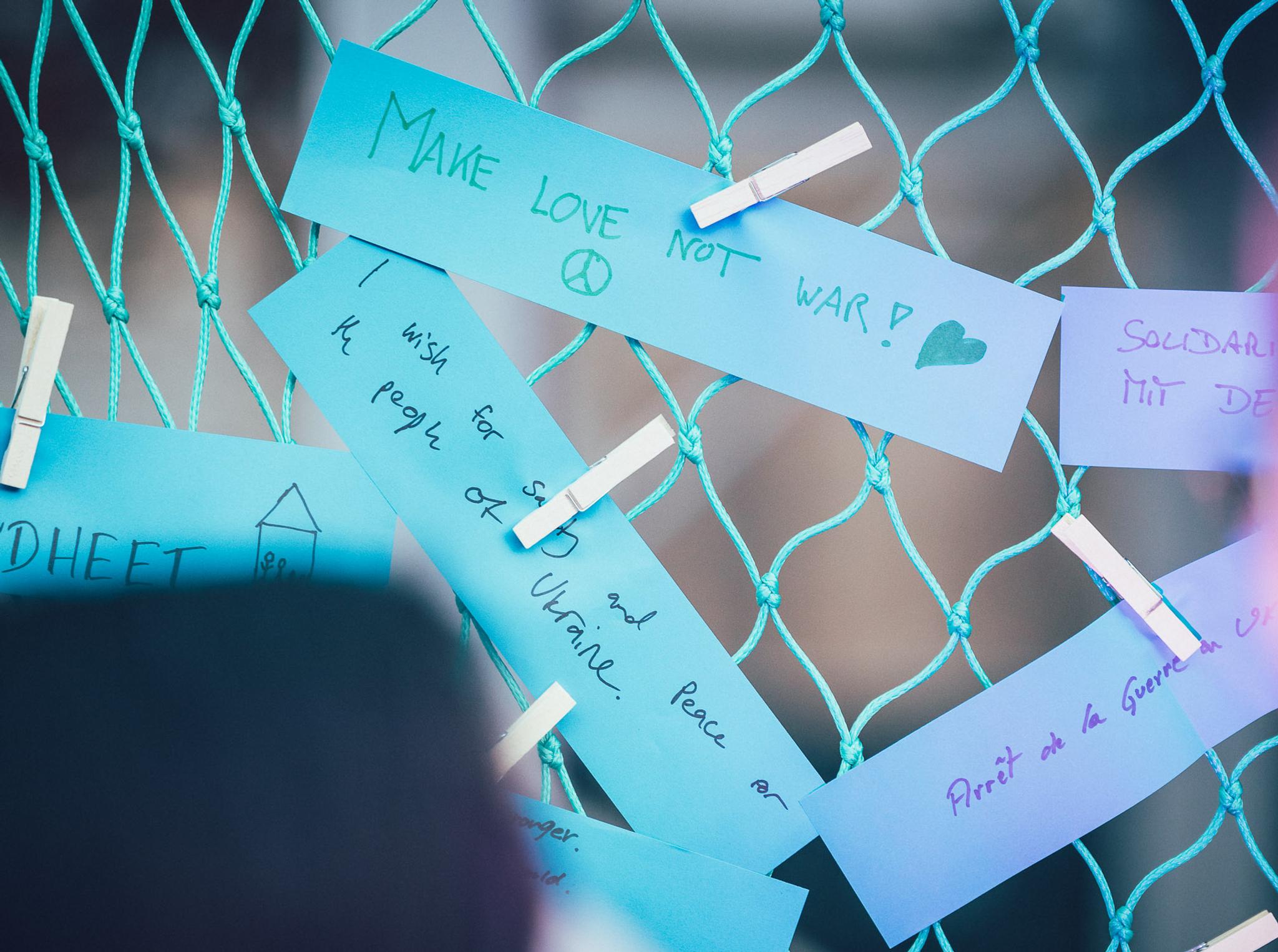 Handwritten notes on a fishnet: "make love not war," and "I wish for safety and peace for the people of Ukraine."
