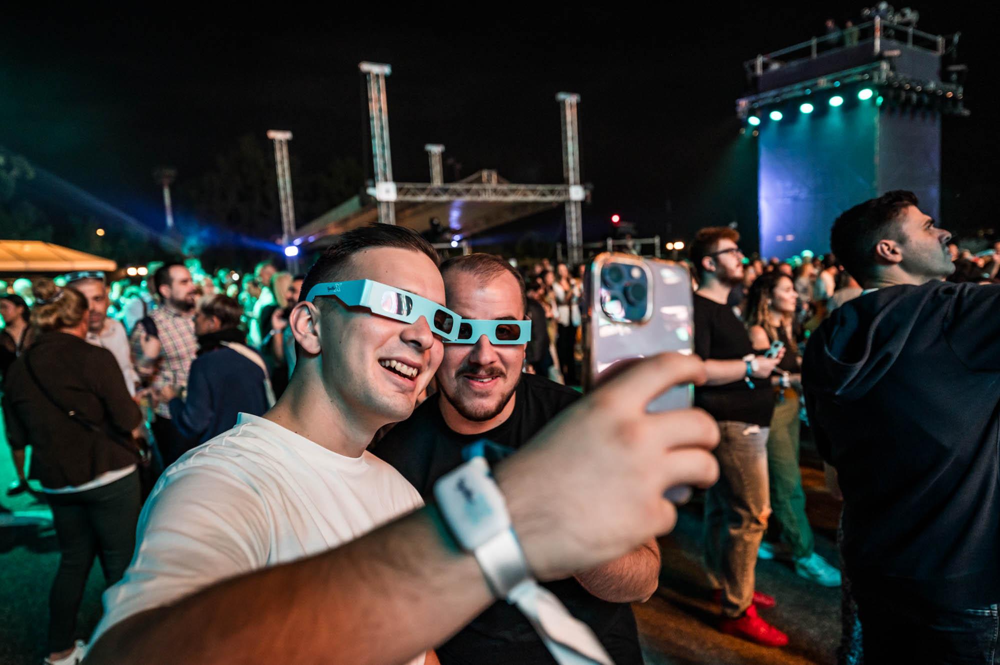 Two men  wearing 3D glasses with a crowd and stage in the background at The Together X Event by Battle Royal Studios