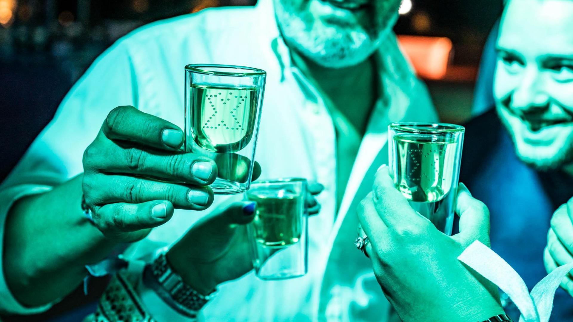 Men holding shot glass with an X floating in the liquid at the Together X Event by Battle Royal Studios