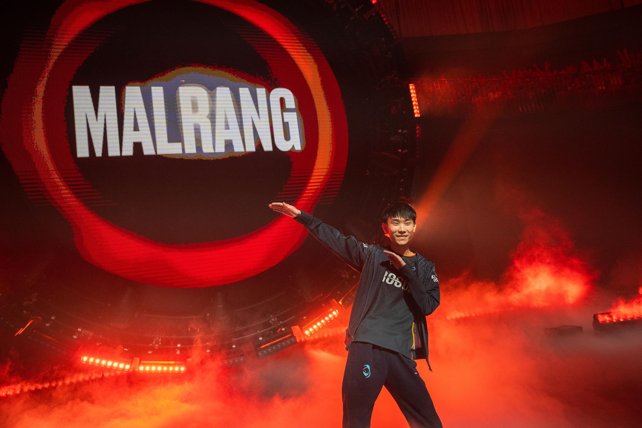 A man makes a dabbing movement in front of the light installation which reads "MALRANG."