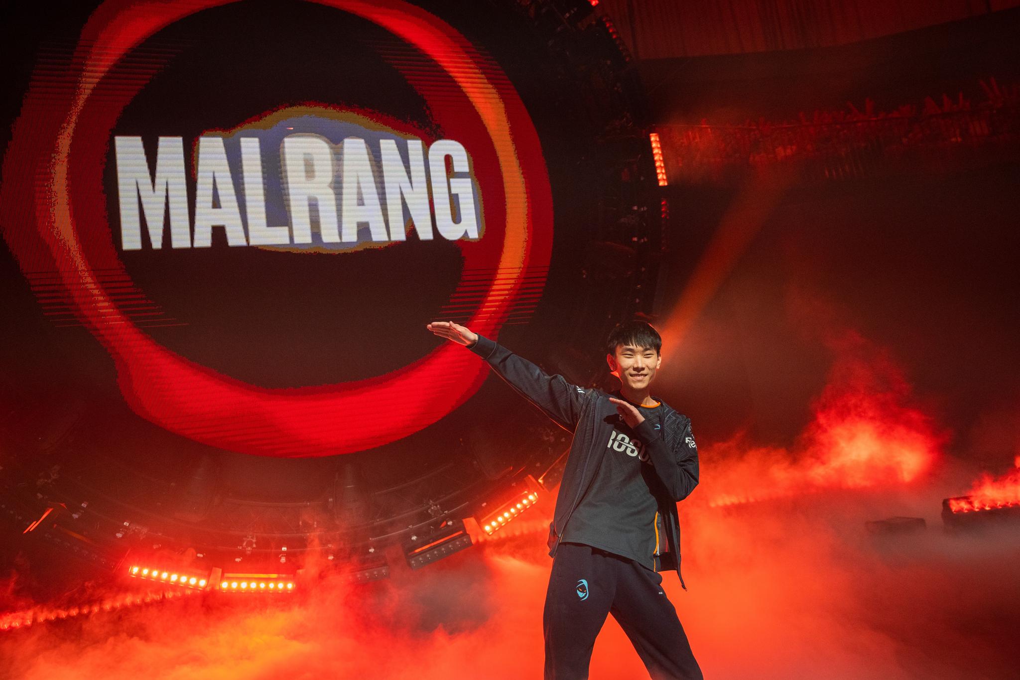A man makes a dabbing movement in front of the light installation which reads "MALRANG."