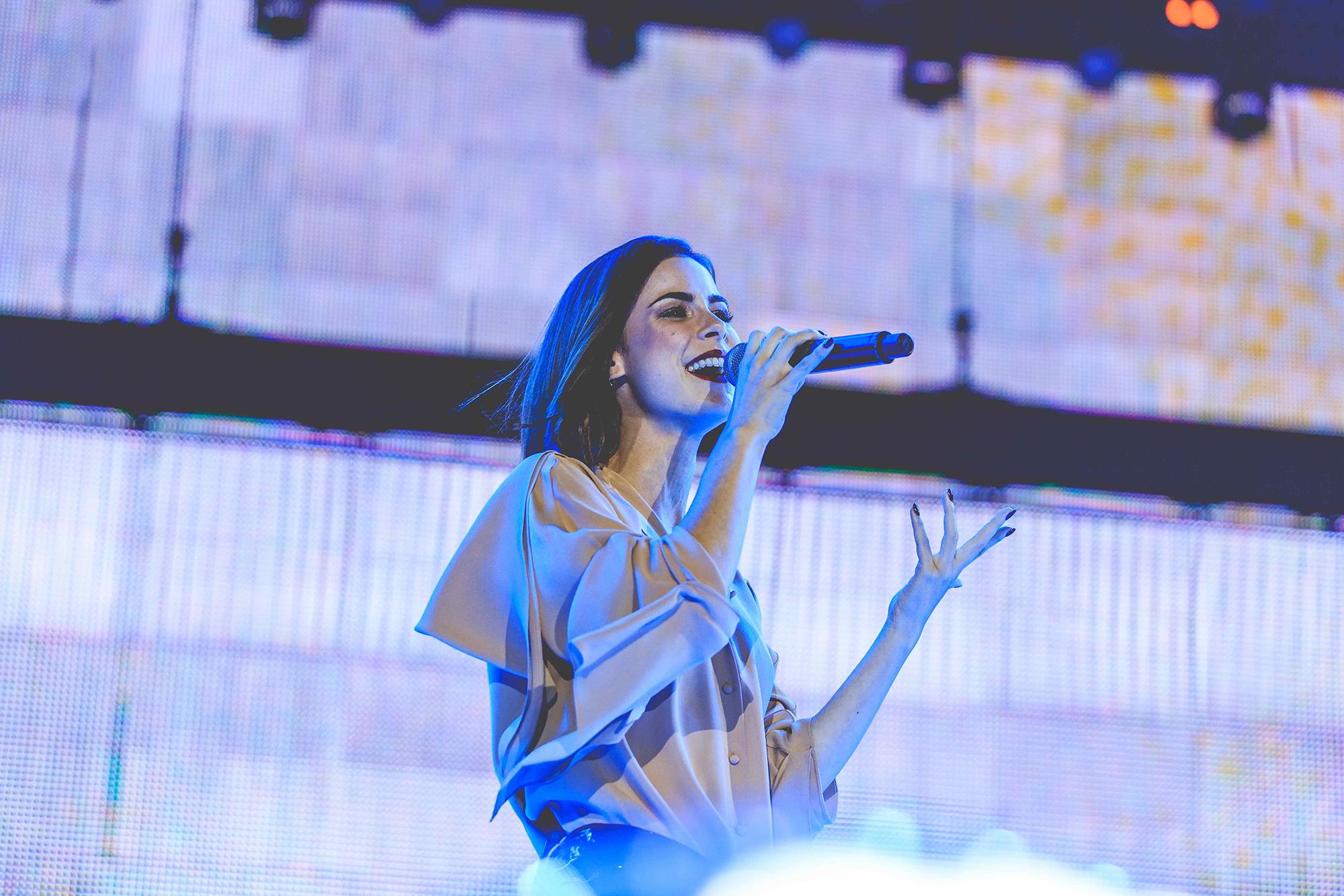 A singer performs on stage with a wall of LEDs behind her.