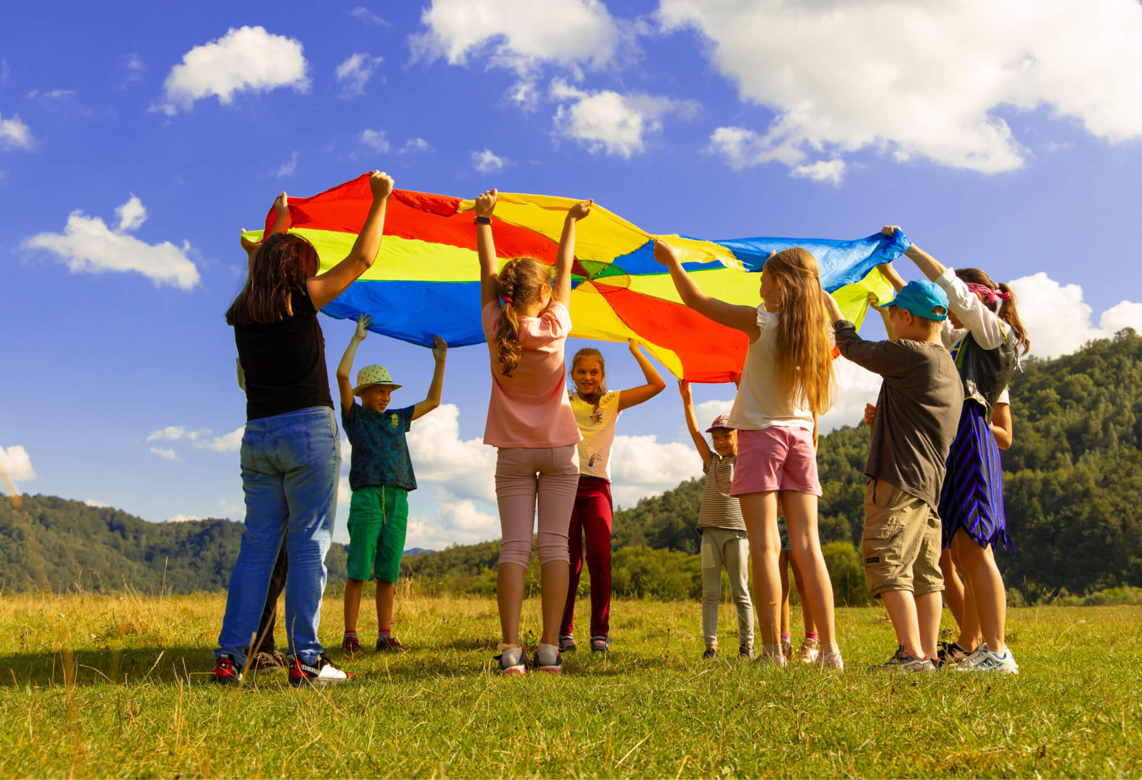 A group of children play games with a colorful parachute.