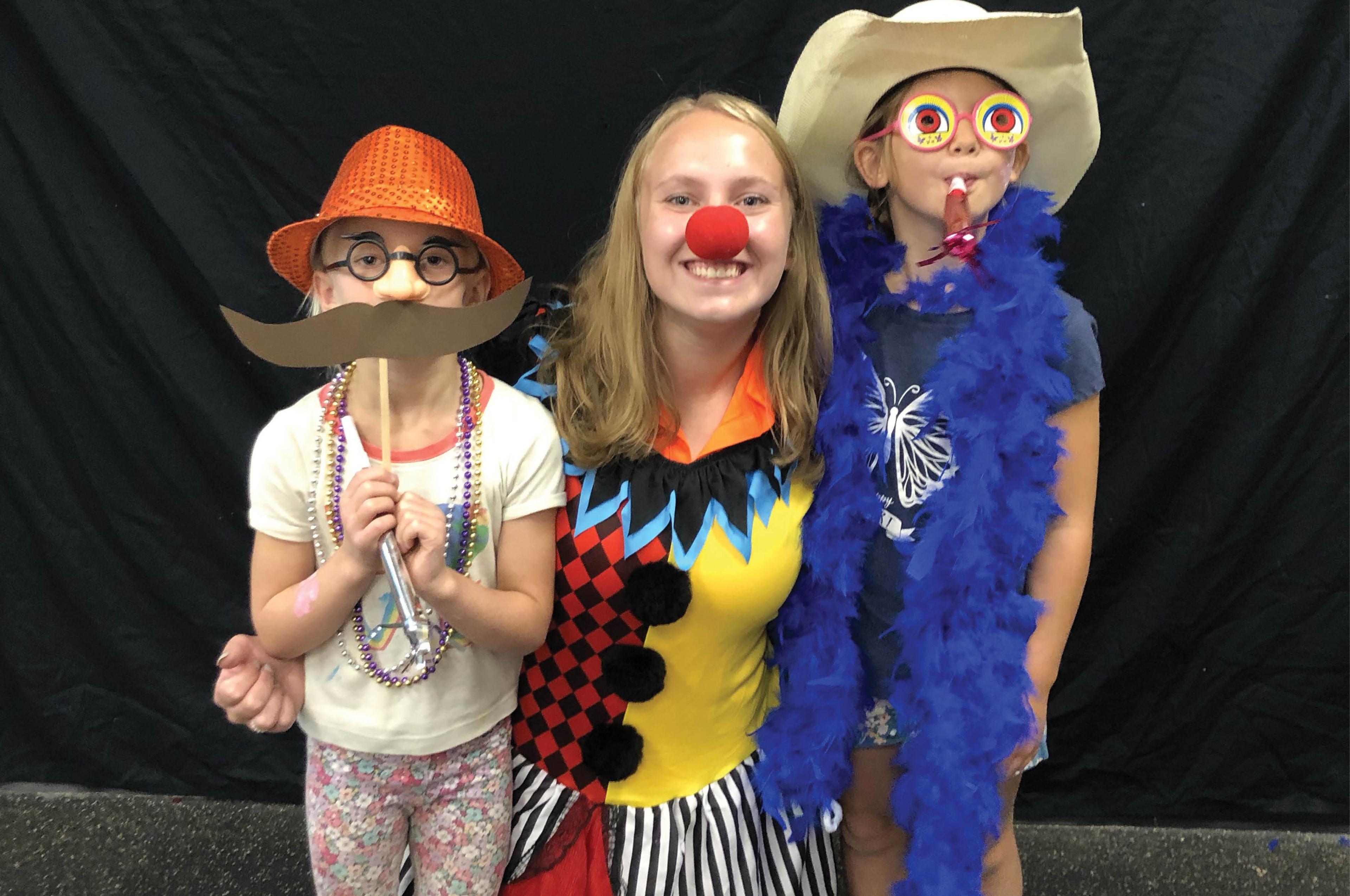 Group of smiling people wearing fun costumes at a day camp.