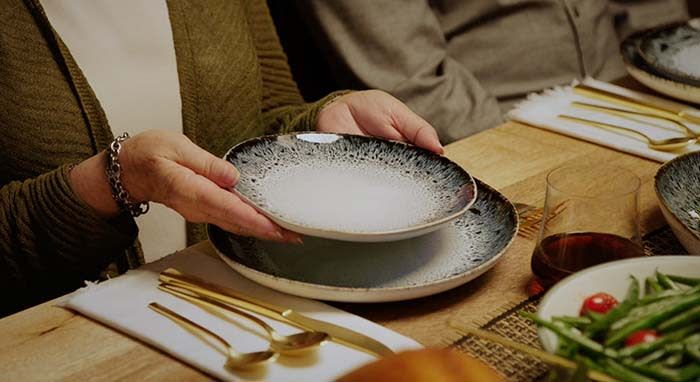 close up shot of a set dinner table with a woman holding a plate above another plate