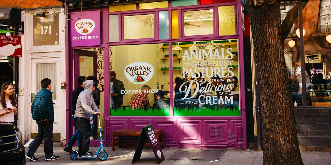 a purple coffeeshop in new york advertising coffee and cream with people outside looking in