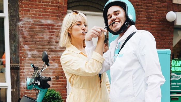 A man and a woman lock arms and brush their teeth simultaneously in the streets of new york