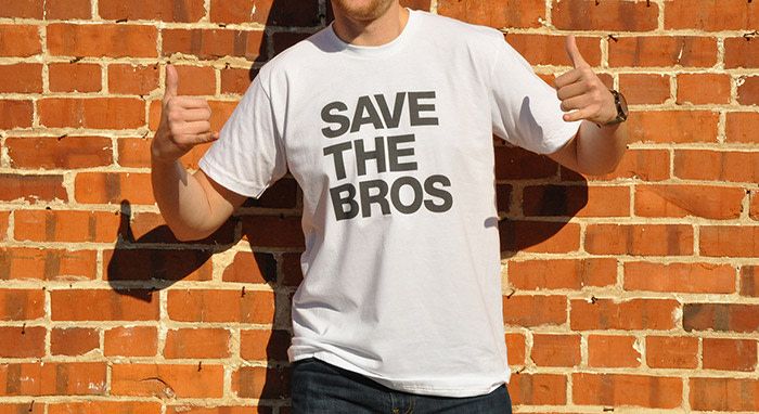 a man in front of a brick wall wears a white t shirt that reads, "save the bros"