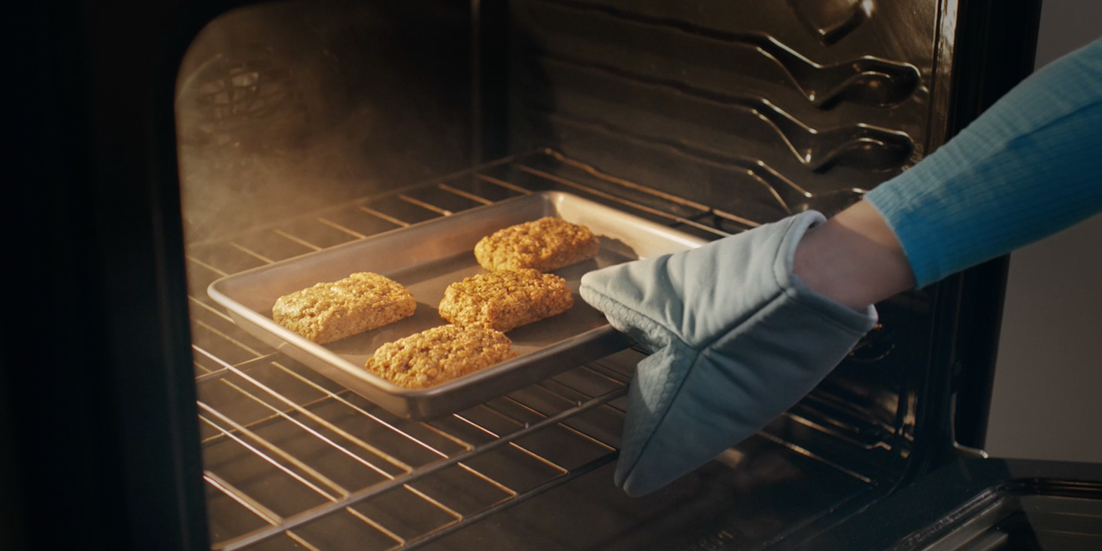 A hand reaches into an oven to take out bobo's while baking