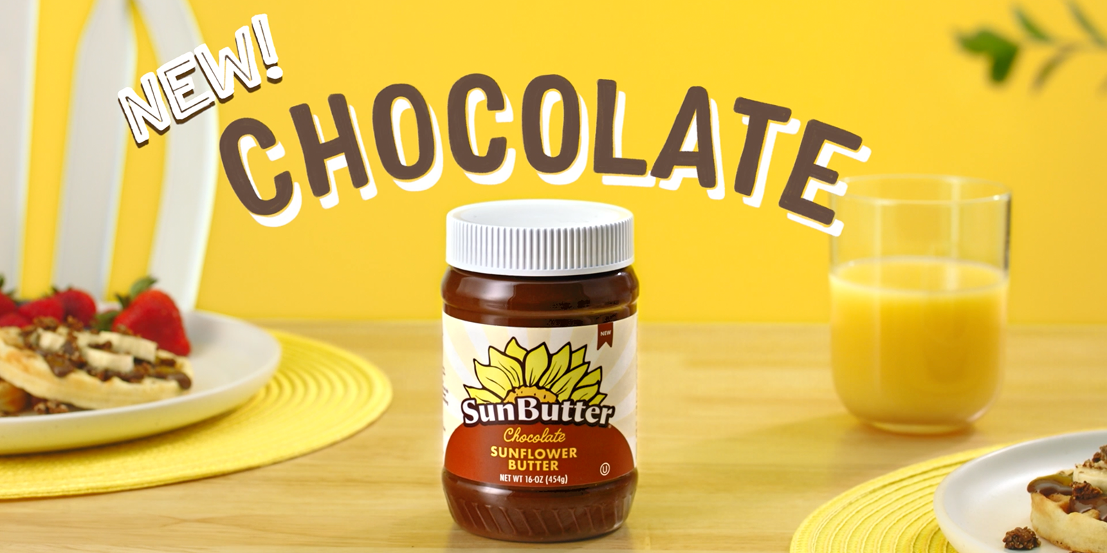 the words, "New Chocolate" is displayed over sunbutter sitting on a table next to two plates of waffles and orange juice