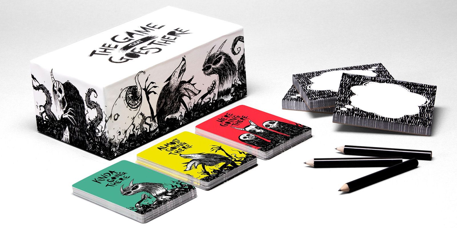 A card game with multiple stacks of cards, pencils, and the game box