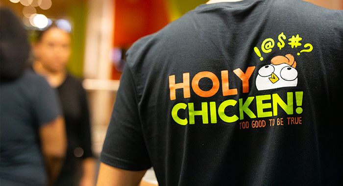 the back of the worker's shirt for Holy Chicken