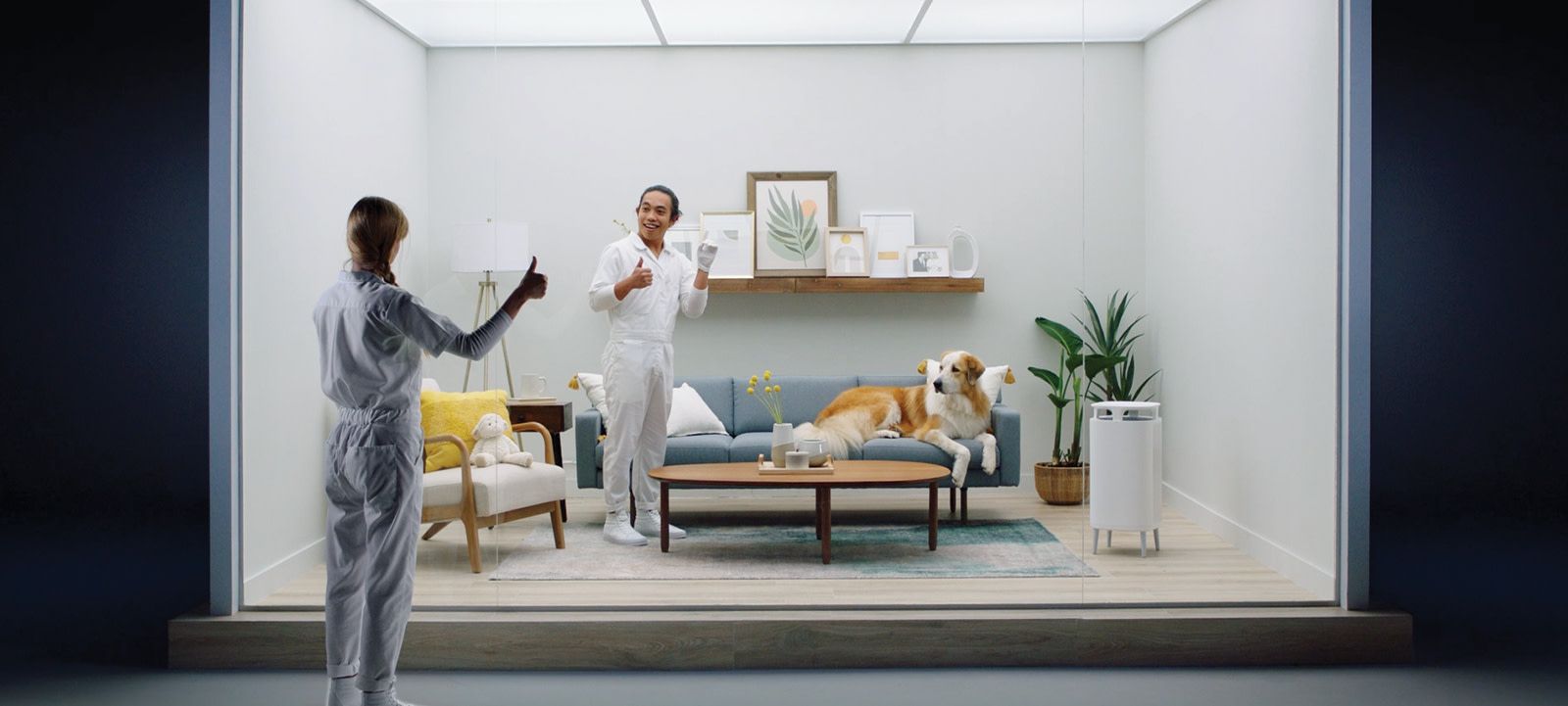 two men looking through glass giving each other thumbs up into a staged living room with a dog on the couch