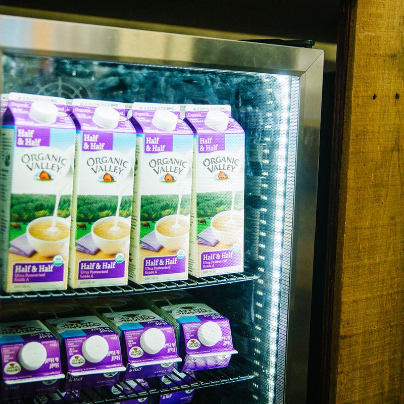 Close up shot of a refrigerator with a glass door containing organic valley half and half