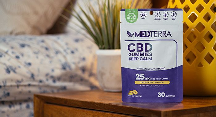 Med terra cbd gummies sit on a bedside table with the bed in the background