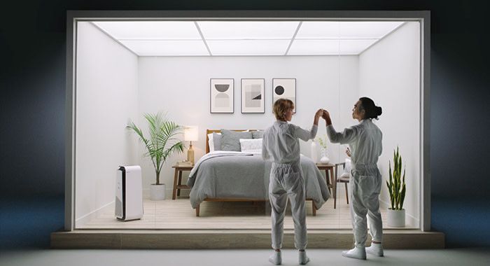 two people fist bumping outside of an enclosed bedroom set with a blue air purifier in the room