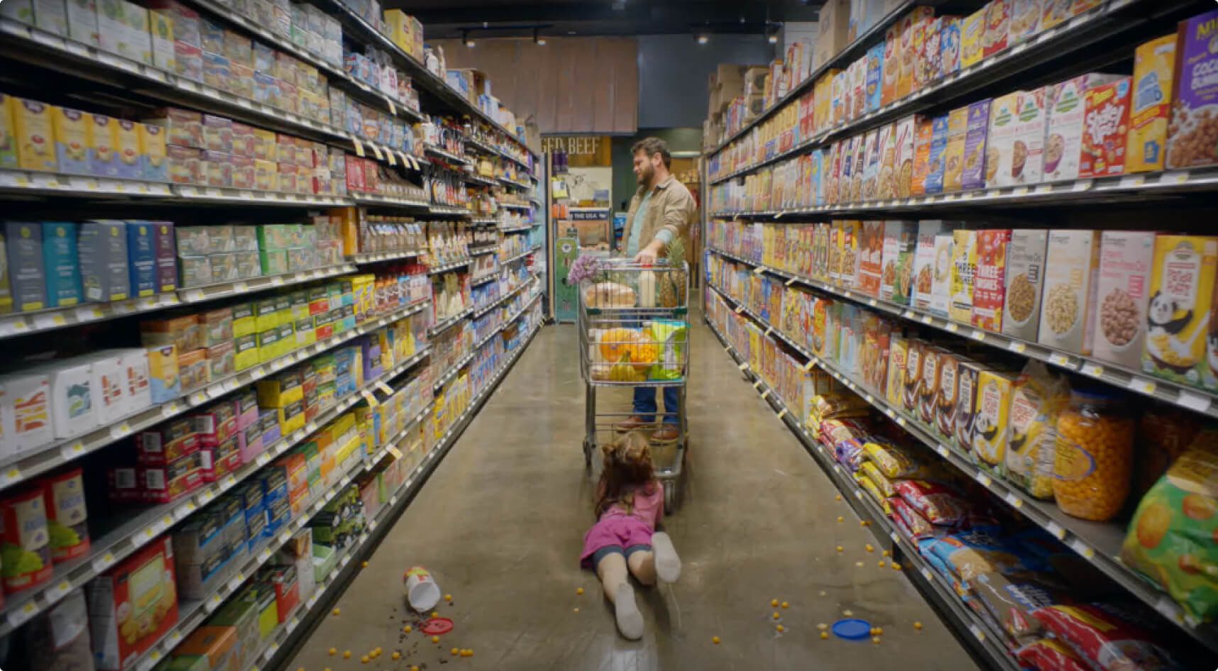 A man attempts to ignore the fact that his child is lying on the floor pitching a fit while he shops for groceries