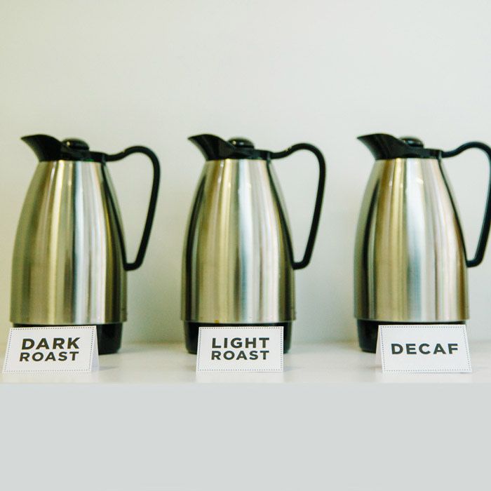 three pitchers of coffee each with a sign in front of them telling if it is either dar roast, light roast, or decaf