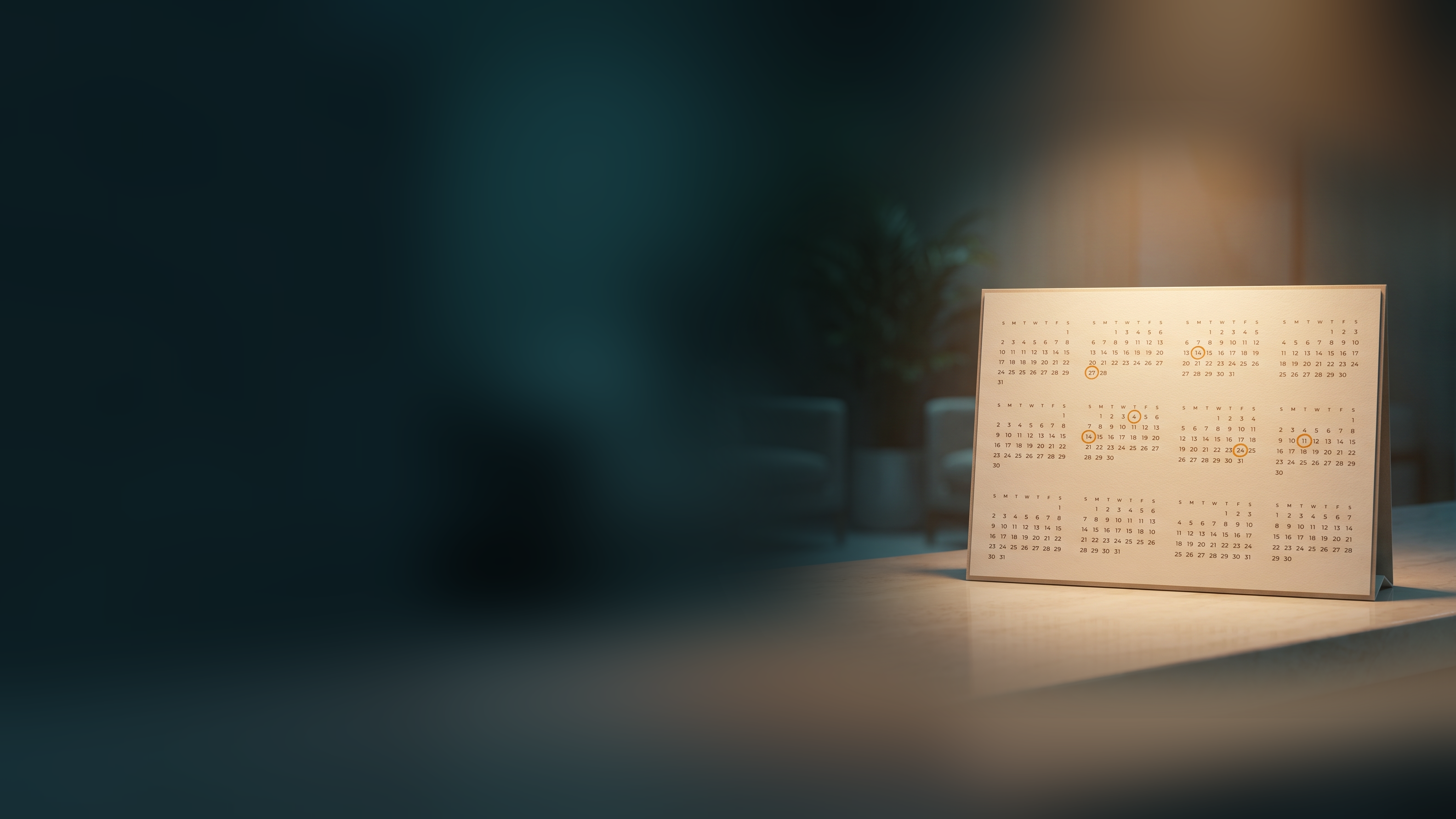 A year-at-a-glance desk calendar on a reception counter with several appointment dates circled in amber