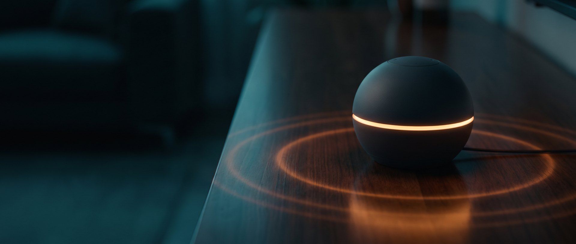 A black smart speaker with a glowing amber ring sitting on a dark wooden table, rings of light spreading across the surface around it.