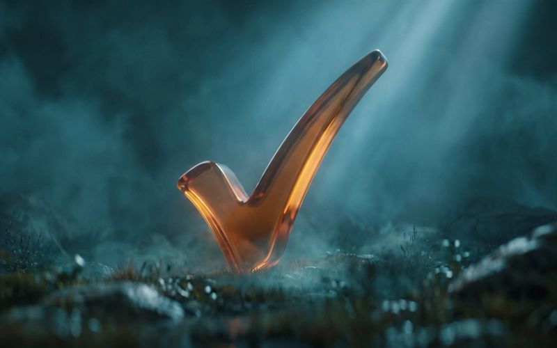 A glowing amber checkmark standing upright on dark, misty ground under a shaft of light.