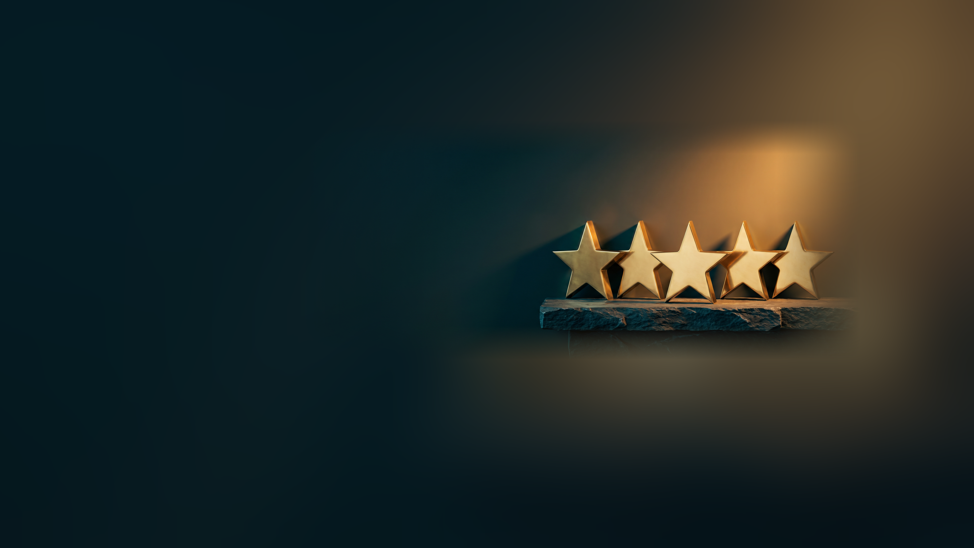 Five solid gold stars standing in a row on a dark stone ledge in warm light