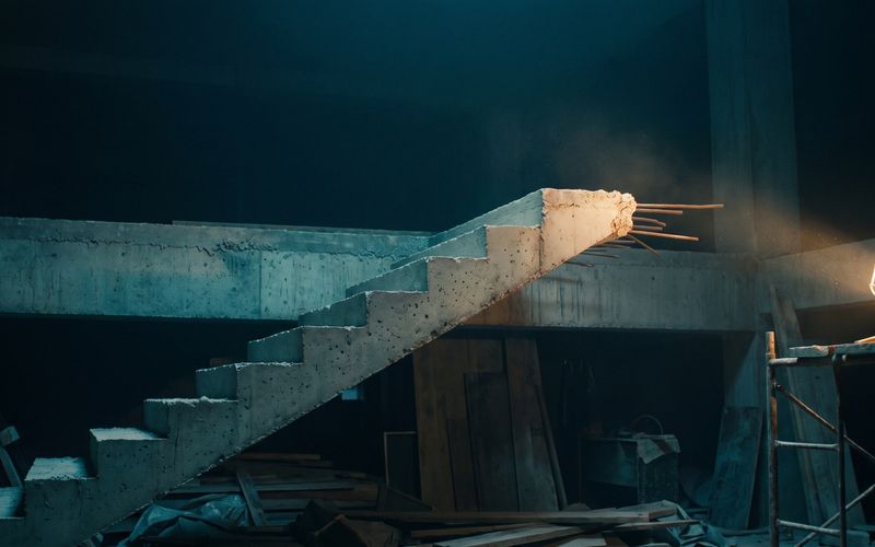 A concrete staircase in an unfinished building that stops partway and ends in open air