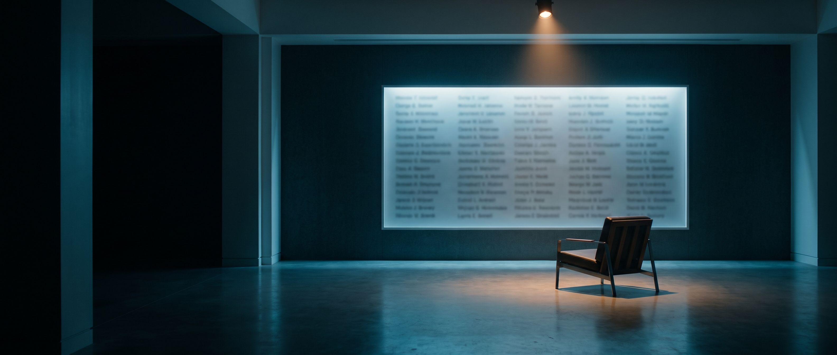 A wall of illuminated name rows lit in a dark empty room, with a single empty chair facing it