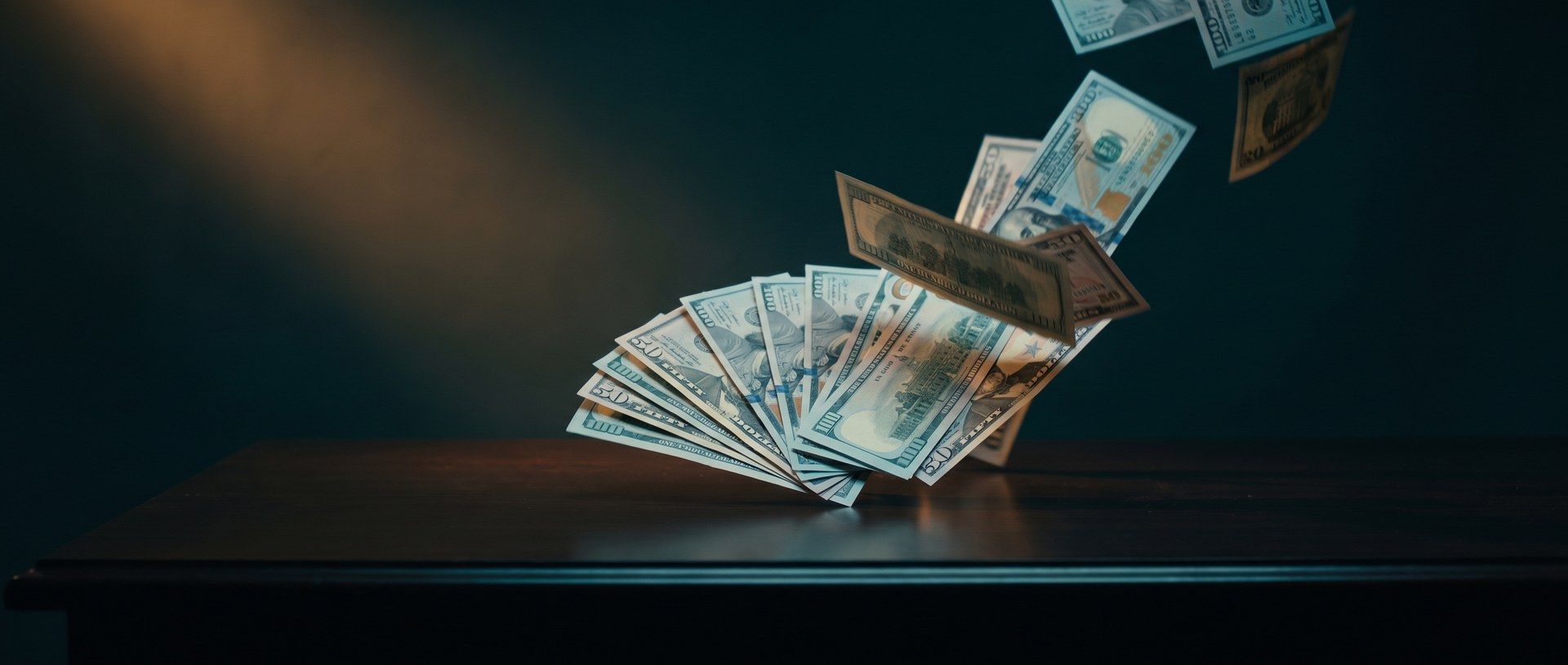 Banknotes lifting off a dark desk and scattering into the air