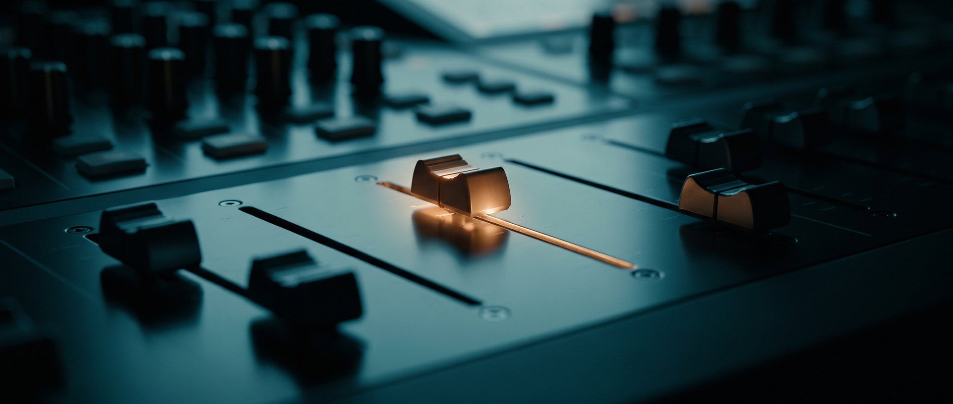 A row of mixing-desk faders left down with a single fader pushed up and lit