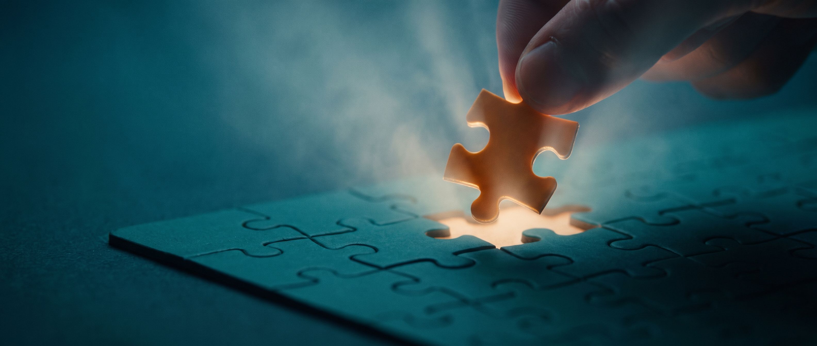 Fingertips lowering a single warm-amber puzzle piece into the last empty gap of a deep teal jigsaw, the moment a ready buyer confirms the thing actually fits.