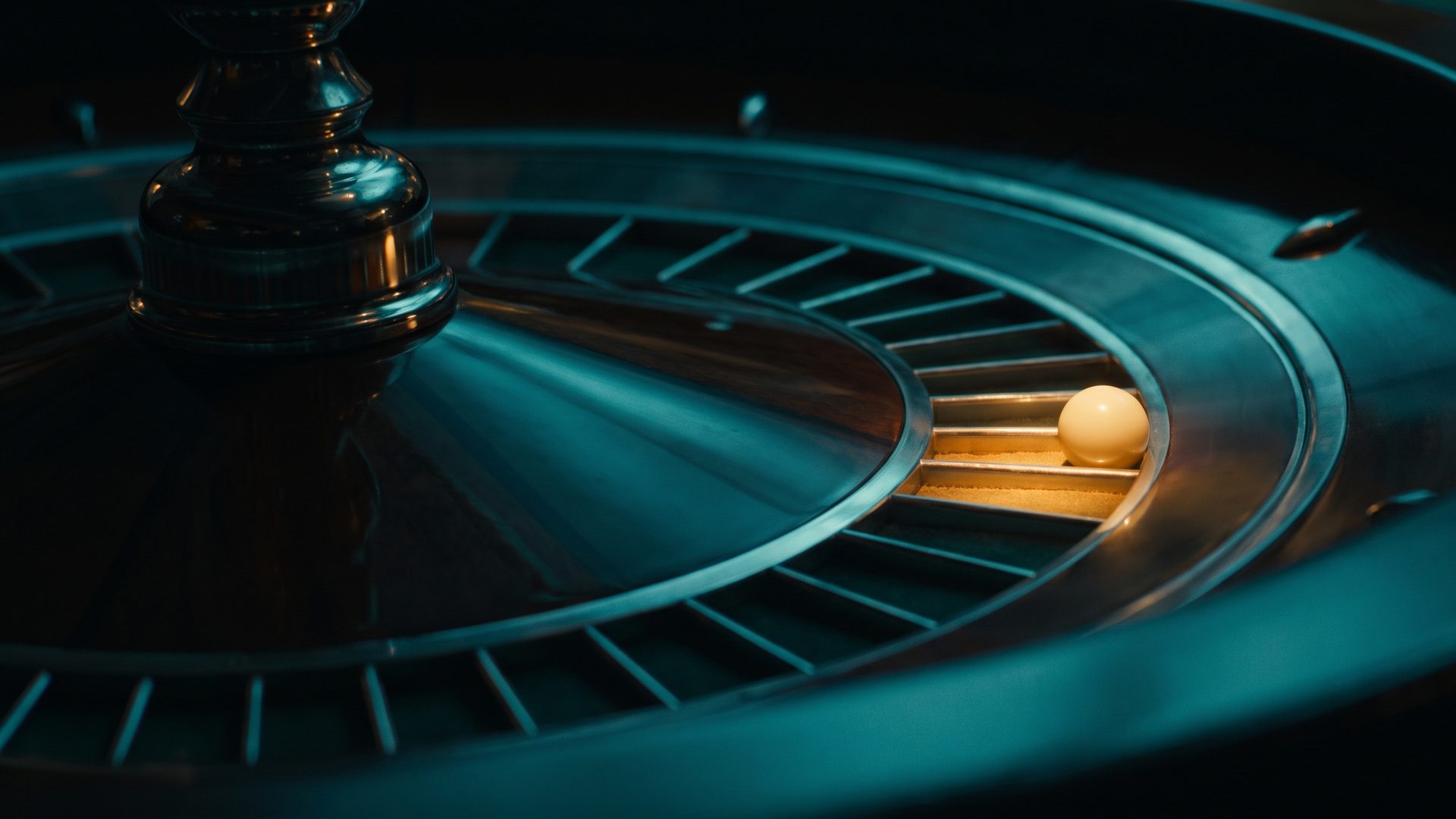 A roulette wheel in deep teal with one amber-lit pocket and the ball come to rest in it.