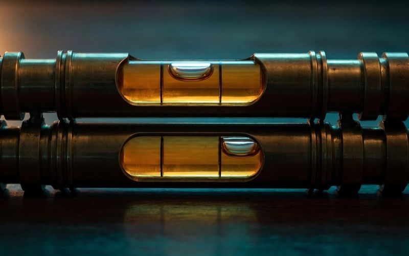 Two brass spirit levels resting on the same surface with their bubbles sitting in different positions