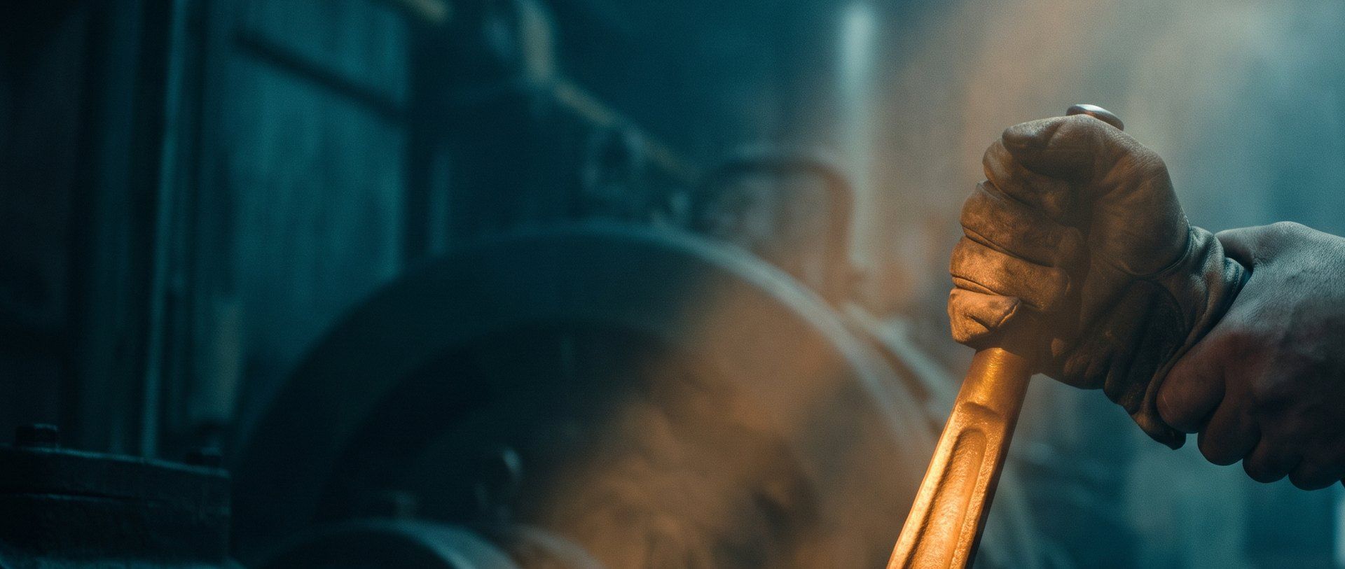 A gloved hand gripping a heavy amber-lit machine lever that is not moving