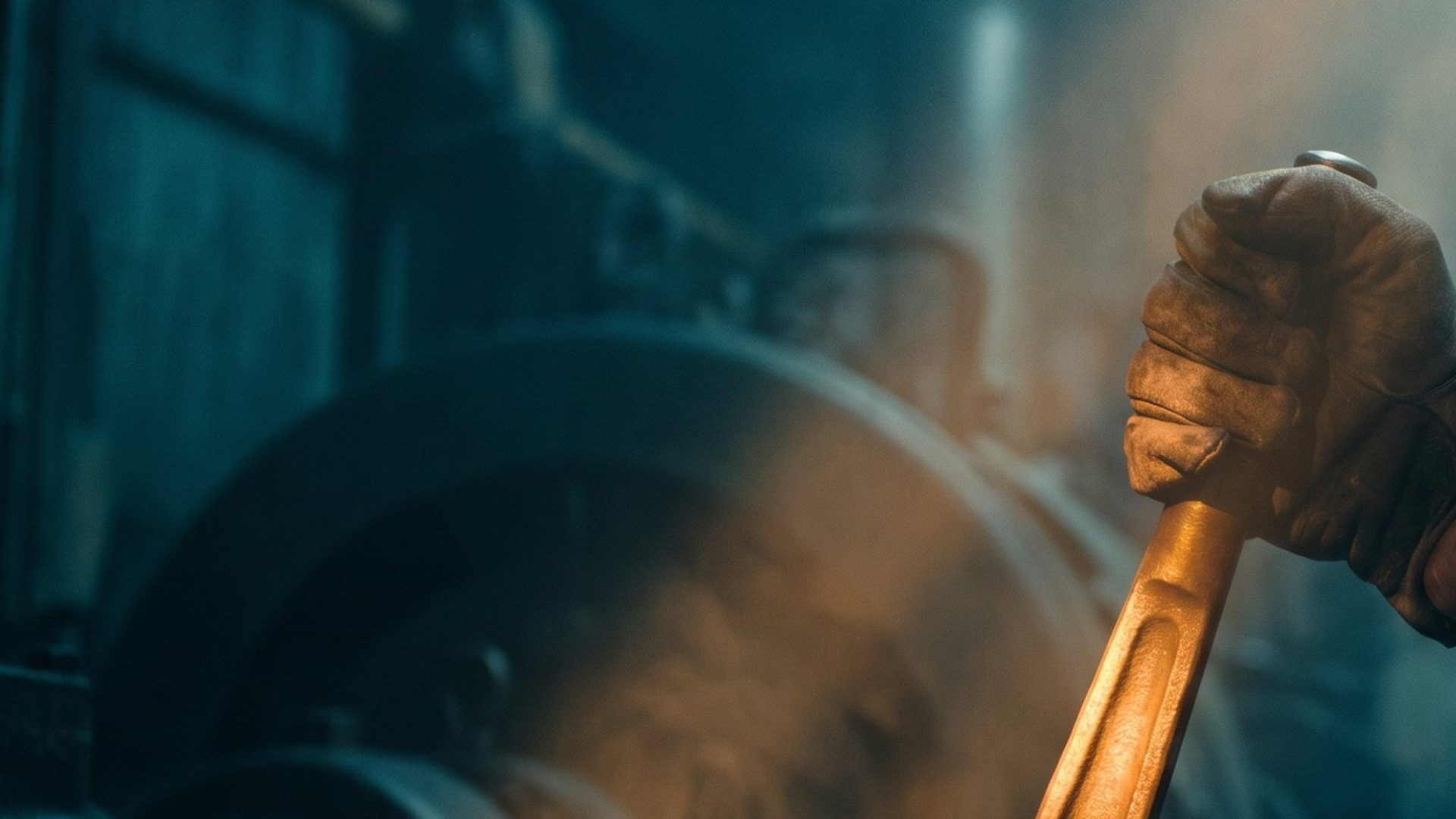 A gloved hand gripping a heavy amber-lit machine lever that is not moving
